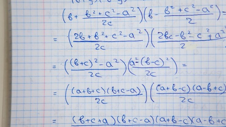 Handwritten physics equations on graph paper show active problem work instead of passive study