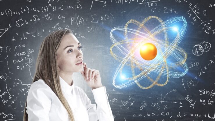 Student looks at a chalkboard with equations and an atom diagram while think about physics concepts