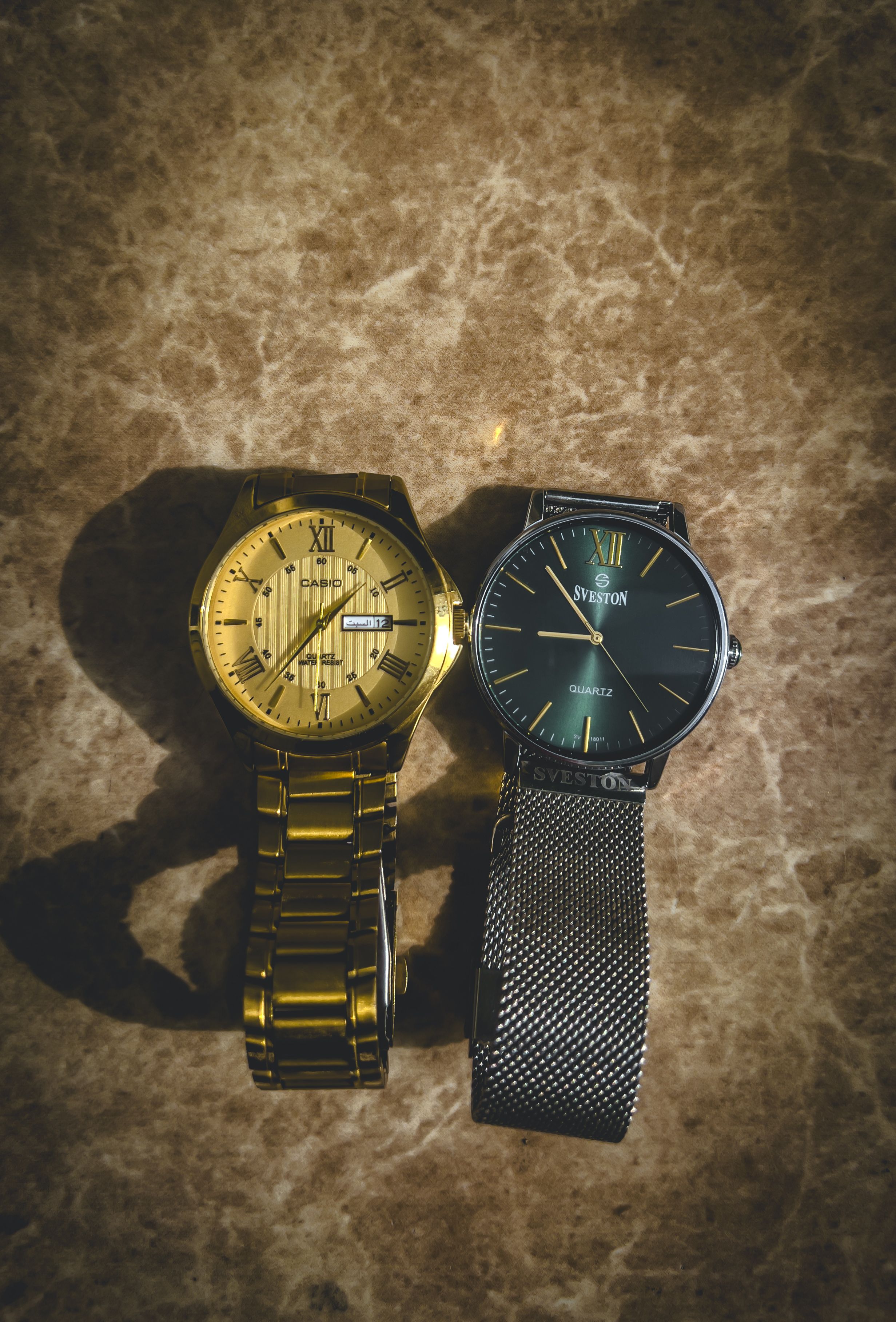 Close-up of gold and silver luxury wristwatches on a marble background, representing premium goods