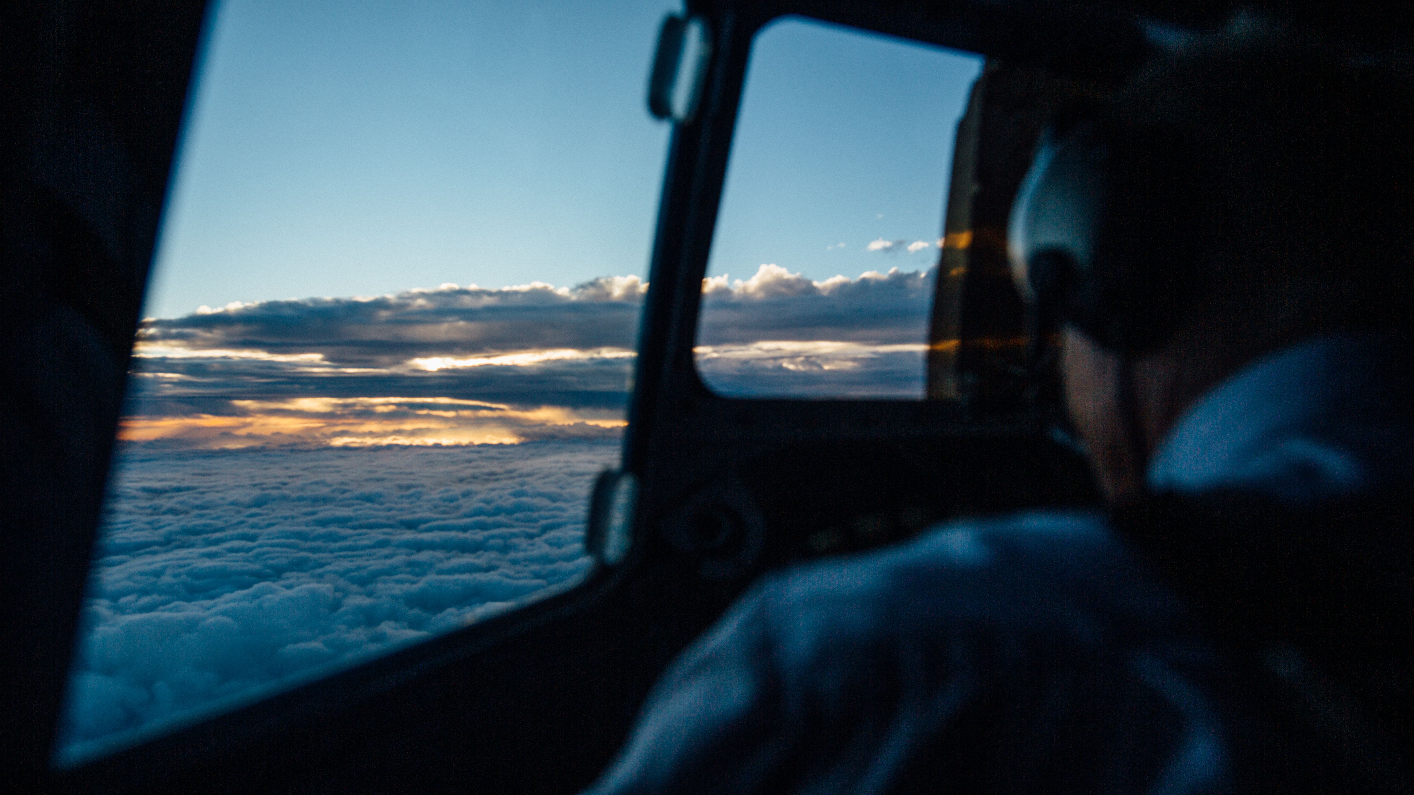 View from an airplane cockpit above clouds at sunset, evoking the flight imagery associated with Aviator.