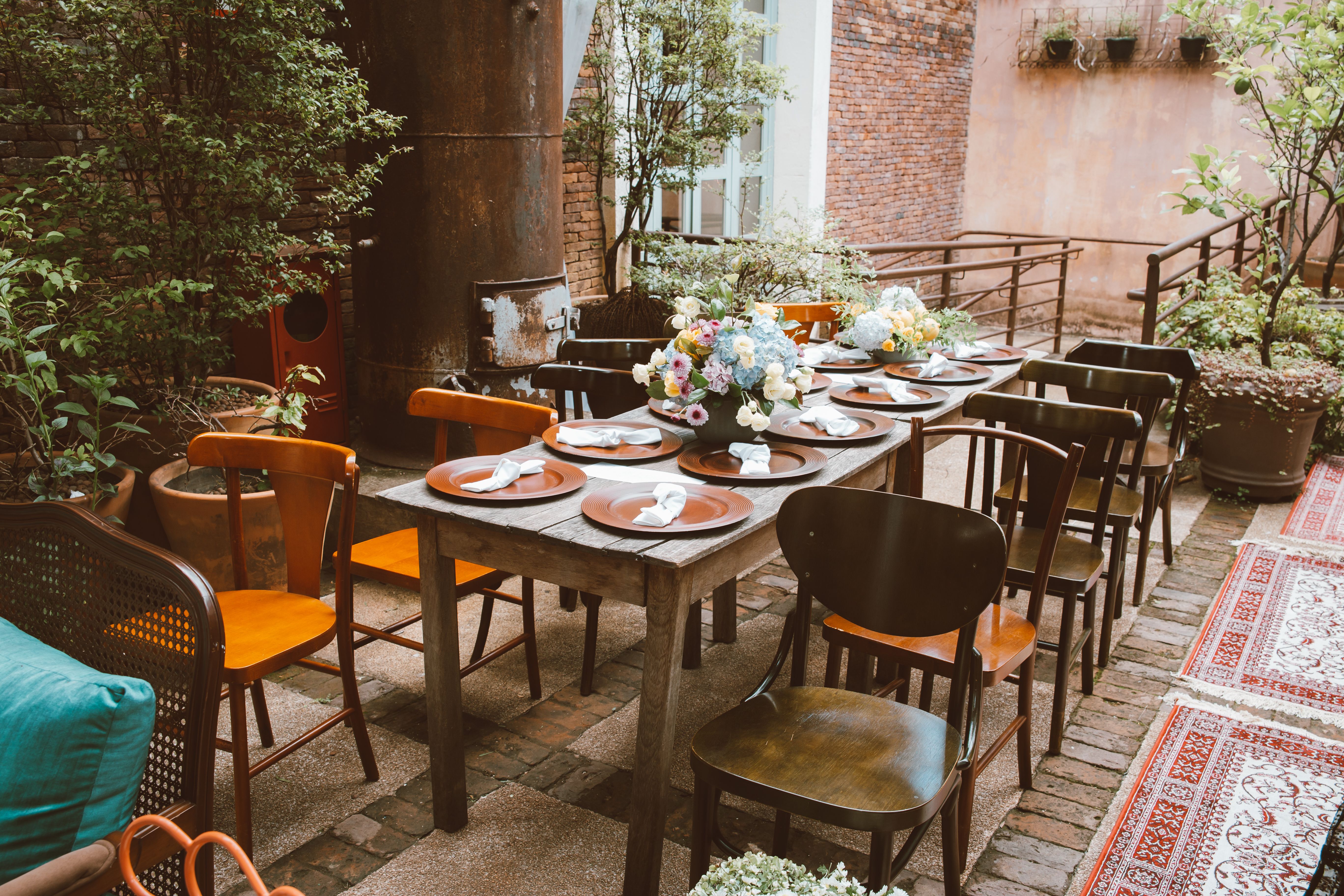 Beautiful rustic table setting outdoors with flowers and wooden chairs.
